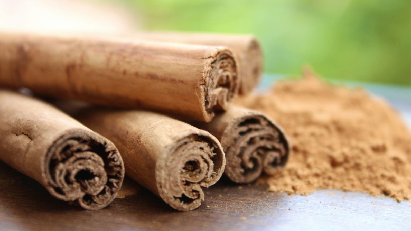 Bâtons de cannelle de Ceylan aux fines couches enroulées, à côté d'une coupelle de poudre brun clair et de gélules