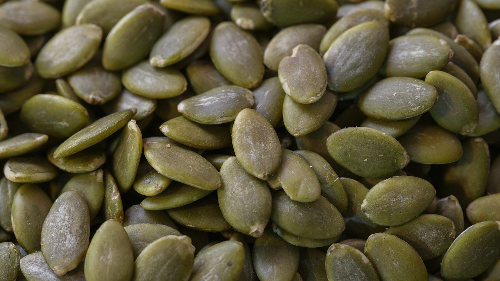 Huîtres ouvertes, graines de courge, lentilles et morceau de fromage disposés sur une planche en bois