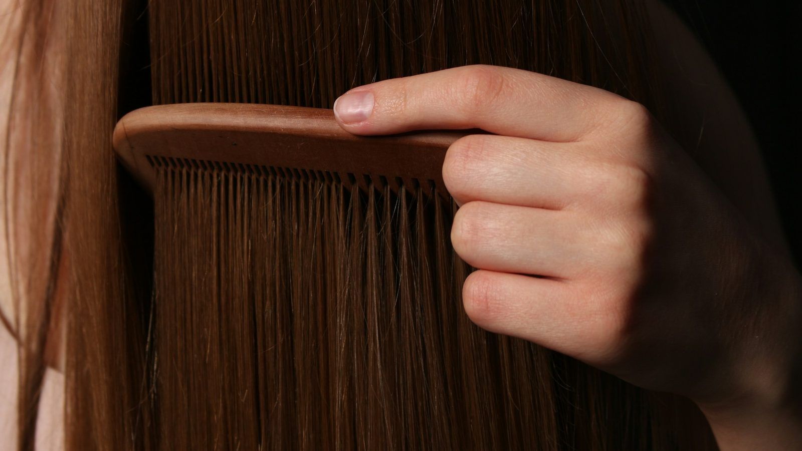 Brosse en bois avec quelques cheveux, posée à côté de gélules et de graines de courge sur un plan de travail clair