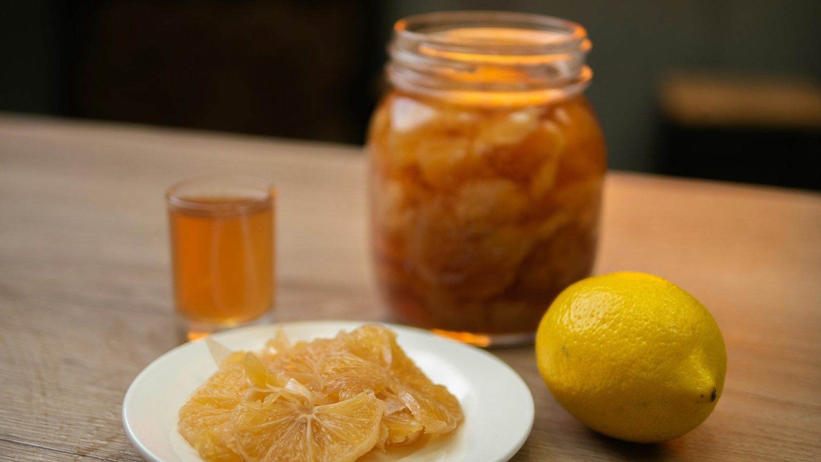 Gélules de vitamine D, oranges coupées et pot de propolis sur une table en bois en lumière d'hiver