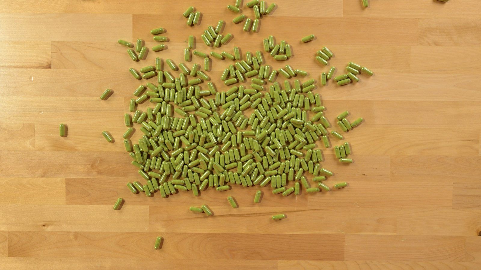 Feuilles séchées de desmodium et gélules végétales sur une table en bois clair