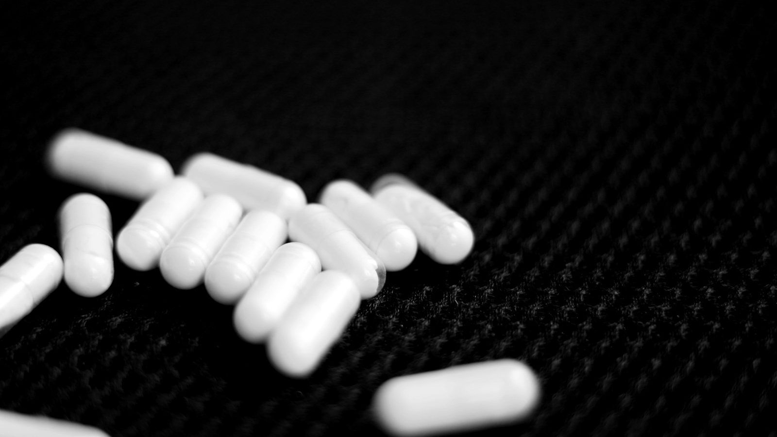 Poudre blanche de myo-inositol dans une cuillère doseuse, à côté de gélules végétales sur une table en bois clair