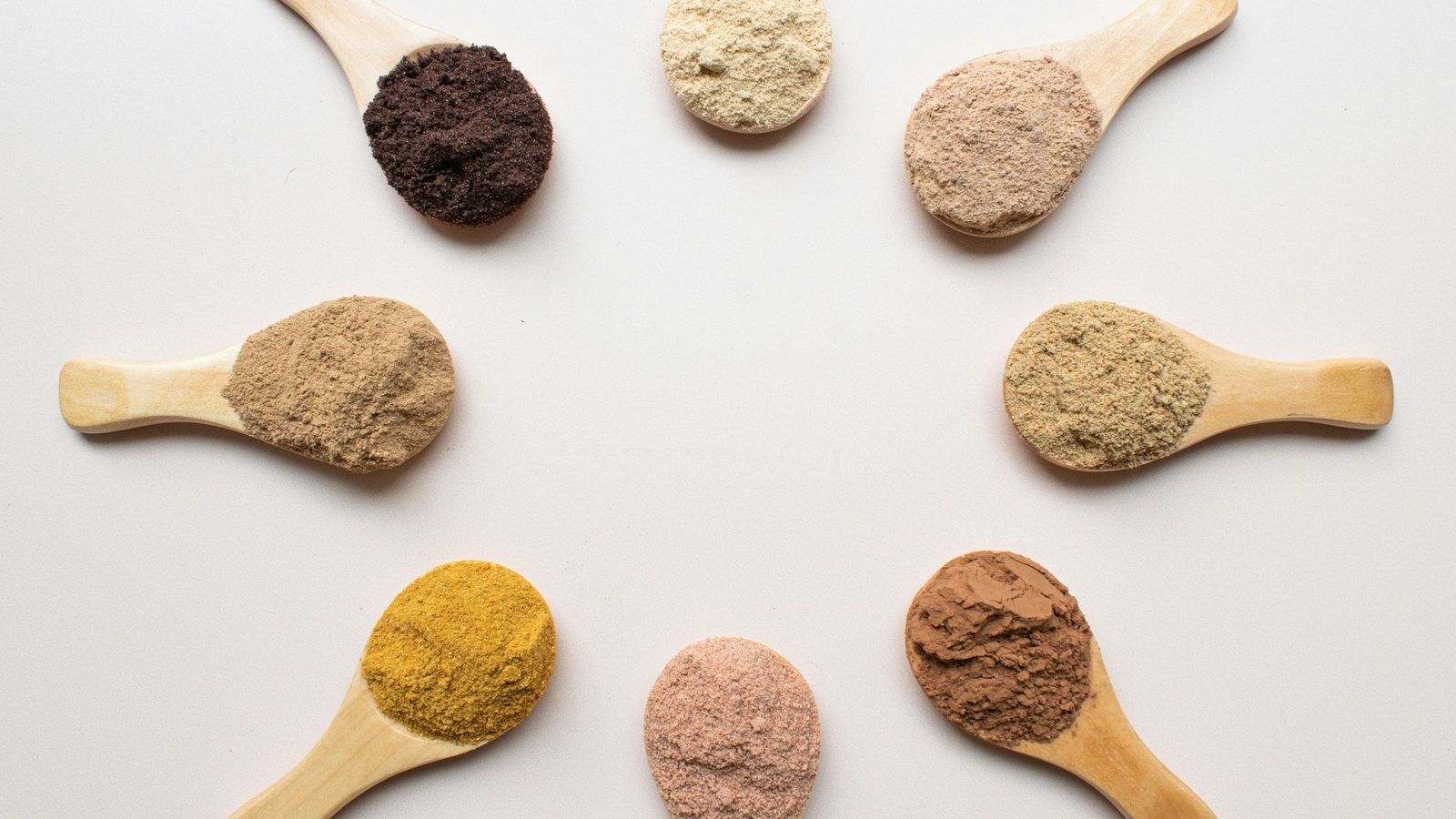 Racines de maca rouges, jaunes et noires posées à côté d'un bol de poudre de maca beige