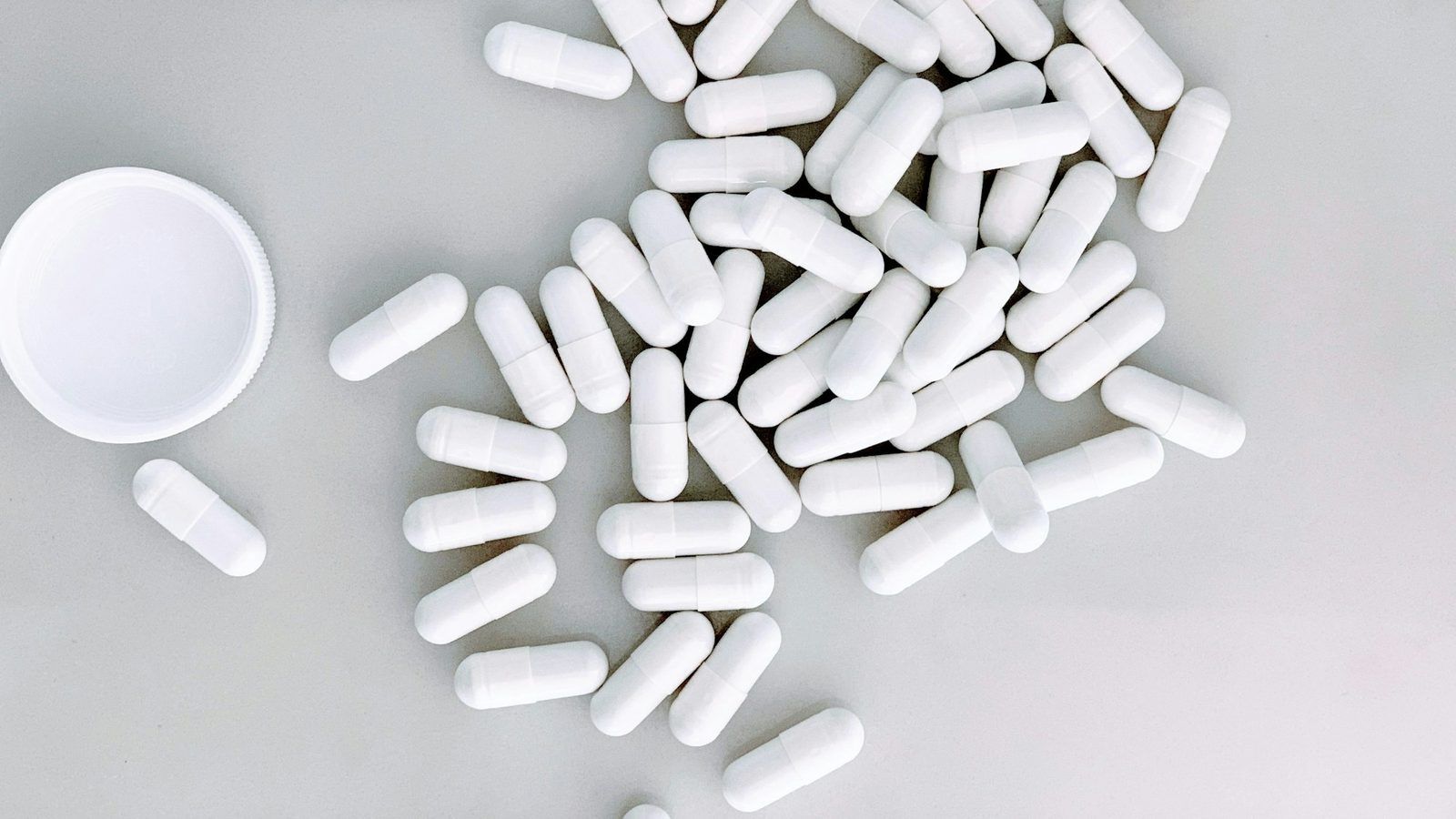 Gélules blanches de N-acétylcystéine et poudre cristalline blanche dans une coupelle en verre
