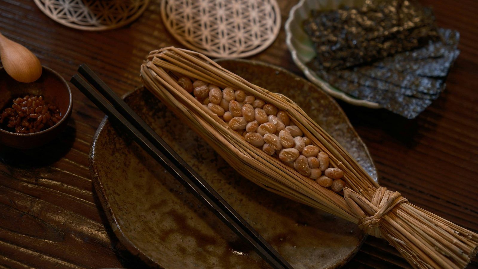 Bol de natto, des graines de soja fermentées aux filaments collants, à côté de quelques gélules blanches