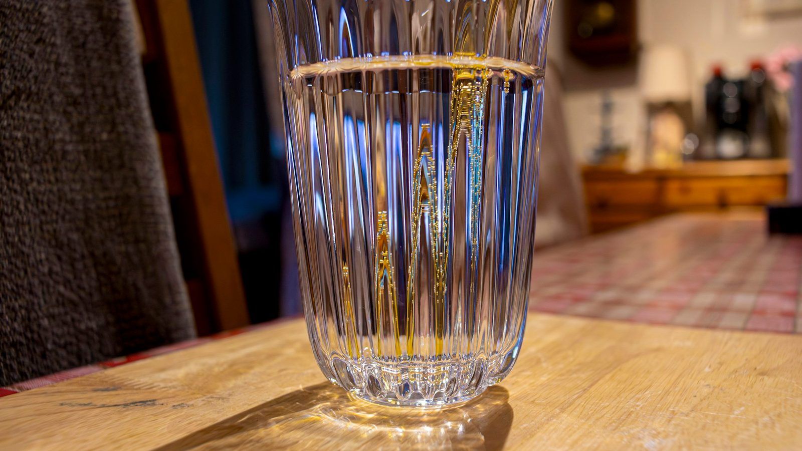 Téguments de psyllium blond dans une coupelle en bois à côté d'un grand verre d'eau